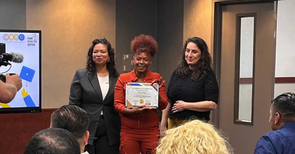 A graduate from the newly launched Worker Education and Resource Center Program proudly presents her certificate.